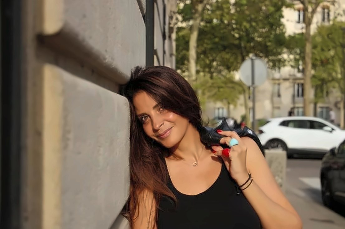 SEYA souriante, adossée à un mur en pierre